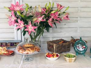 a table with a vase of pink flowers and food at Villa dei Ginepri in Gallipoli