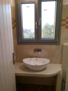 a bathroom with a white sink and two windows at Infinity Apartments in Naxos Chora