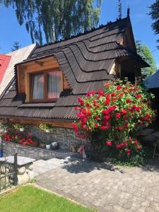 una piccola casa con fiori rossi davanti di Domek na Harendzie a Zakopane