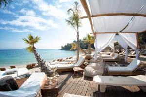 a beach with many lounge chairs and the ocean at Sofimel Apartment in Skala Sotiros
