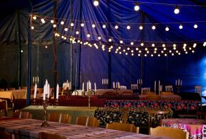 a blue tent with tables and chairs and lights at Cirkus Hostel Holken in Inkoo
