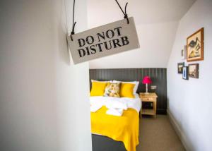 a bedroom with a yellow bed and a sign that says do not disturb at Dunstan House in Burnham on Sea