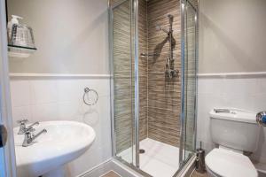 a bathroom with a shower and a toilet and a sink at Dunstan House in Burnham on Sea