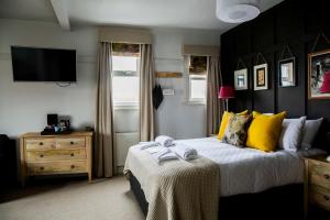 a bedroom with a bed with yellow pillows and a television at Dunstan House in Burnham on Sea