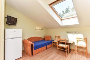 a room with a bed and a table and a refrigerator at Nakvynė pas Romą in Nida