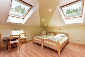 a bedroom with a bed and a desk and two windows at Nakvynė pas Romą in Nida