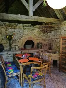 a table and chairs in a stone room with a fireplace at La vignolle in Saint-Amand-de-Coly