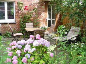 un jardín con flores rosas, mesa y sillas en Ferienwohnung Riedner en Lüneburg