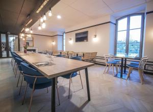 a dining room with tables and chairs and windows at Le Magic Hôtel & Spa - Centre Historique - Climatisation - Parking - Bornes de recharge in Vitré +77 photos