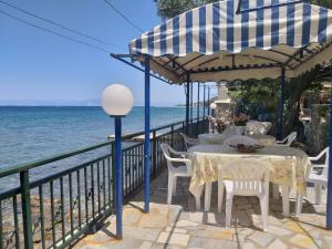 stół i krzesła pod parasolem obok wody w obiekcie Sea View Bungalows w mieście Skala Kallirachis