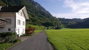 une route menant à une maison blanche dans un champ dans l'établissement Sandras Flat, à Giswil