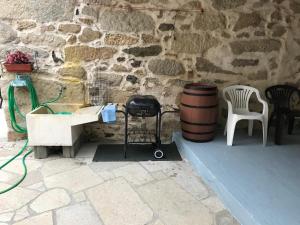 eine Steinmauer mit einem Tisch, einem Stuhl und einem Fass in der Unterkunft Casa Rural Goltar in Goltar