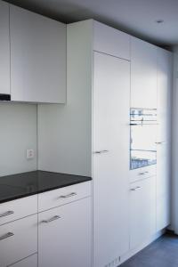 a kitchen with white cabinets and a black counter top at Sandras Flat in Giswil