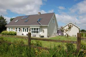 Casa blanca con paneles solares en el techo en The Little Flock Farm en Cloonmore