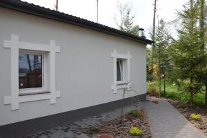 ein weißes Haus mit einem Kreuz an der Seite in der Unterkunft Dom wakacyjny bezpośrednio przy Jeziorze Białym in Okuninka