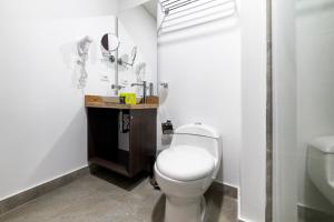 a white bathroom with a toilet and a sink at BOG URBAN HOTEl in Bogotá