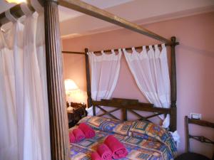 1 dormitorio con cama con dosel y almohadas rosas en B&B Le 2 Cantine, en Castroreale