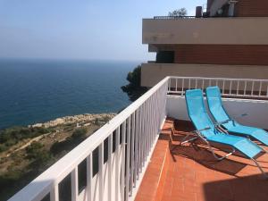 two blue chairs sitting on a balcony overlooking the ocean at SunAndBed ATICO FARO in Salou