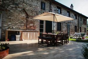 a table and chairs with an umbrella in front of a building at Tipical Tuscany House near Lucca! in Capannori