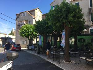 a man standing next to a tree with tables and chairs at Studio Milla in Split