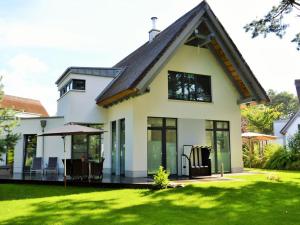 a white house with a conservatory and a lawn at Dat Segelhus in Ostseebad Karlshagen