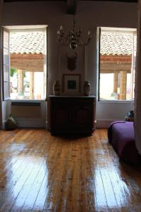 a living room with a wooden floor and two windows at Chambre cozy et Salon de 60 m2 au coeur de la cité in Cordes-sur-Ciel