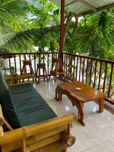 eine Veranda mit einer Bank, einem Tisch und Stühlen in der Unterkunft Cabinas Jimenez in Puerto Jiménez