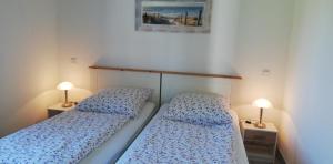 2 Betten in einem kleinen Zimmer mit 2 Lampen in der Unterkunft Ferienhaus Apfelblüte in Twielenfleth