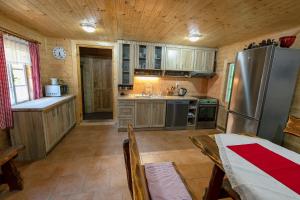eine Küche mit Holzschränken und einem Kühlschrank aus Edelstahl in der Unterkunft Chalupa 47 in Hřensko