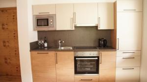 a kitchen with white cabinets and a sink and a microwave at Friatscher Apartment in Nauders