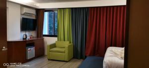 una habitación de hotel con una silla verde y cortinas coloridas en Villa Israel Ecopark El Nido, en El Nido