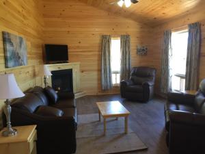 a living room with leather furniture and a fireplace at Cavendish Maples Cottages in Cavendish