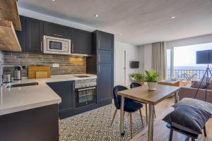 フエンヒロラにあるSur Suites Perla 6 - 2のキッチン(青いキャビネット、テーブル付)、ダイニングルーム