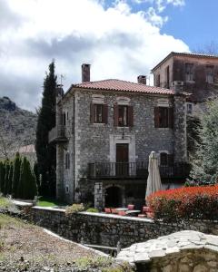 una antigua casa de piedra con un balcón frente a ella en Tsarbou Guesthouse, en Stemnitsa