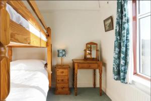 a bedroom with a bunk bed and a table with a mirror at Chy-an-Lowena in Crantock