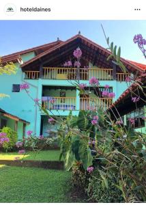 a picture of a house with purple flowers at Hotel da Inês in Visconde De Maua