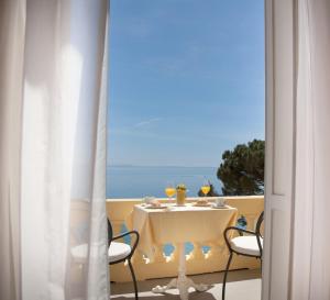 a table with a view of the ocean from a balcony at Hotel Kvarner - Liburnia in Opatija