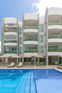 un immeuble d'appartements avec une piscine en face dans l'établissement Wave Suítes Hotel & Lounge bar, à Maceió