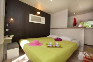 a bedroom with a green bed with pink hats on it at Mobil home Domaine de Soulac in Soulac-sur-Mer
