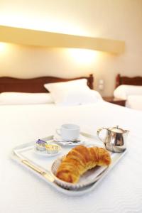 a tray of croissants and coffee on a bed at Hôtel de Paris in Luchon