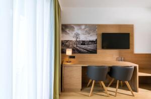 a room with a desk with two chairs and a television at Hotel Garni Sohler in Villach