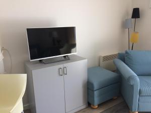 ein Wohnzimmer mit einem TV auf einem Schrank und einem Stuhl in der Unterkunft Bilderdijklaan 8 Château Petit Sable in De Haan