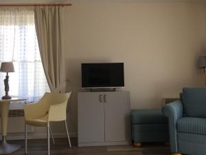 ein Wohnzimmer mit einem TV auf einem Schrank und Stühlen in der Unterkunft Bilderdijklaan 8 Château Petit Sable in De Haan
