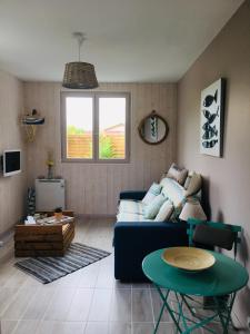 a living room with a blue couch and a table at STUDIO L'ERMITAGE in Gujan-Mestras