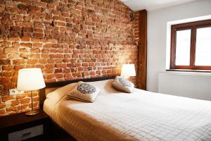 a bedroom with a brick wall and a bed with pillows at Krakow For You Main Square Apartments in Krakow