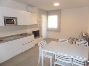 a kitchen and dining room with a white table and chairs at Residence Melograno in Bibione
