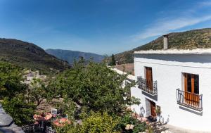 a white building with balconies and a view of mountains at Casa Tita María in Bubión