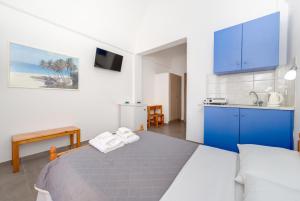 a room with a bed and a kitchen with blue cabinets at Andreas Studio in Perissa