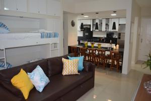 a living room with a brown couch and a kitchen at Sun Paradise - Pio X in Maceió