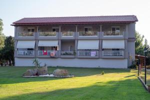 a large white building with a green lawn in front of it at Camping Linaraki Apartments & Bungalows in Sikia
